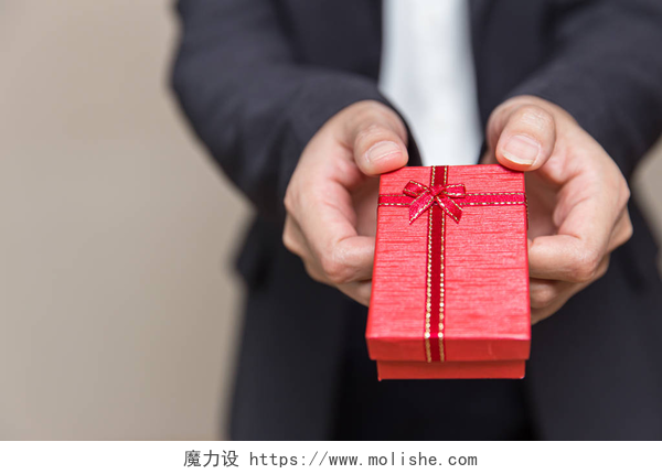 一个商务男人手里拿着一个红色的礼品盒商务办公室手工赠送礼品盒奖赏，并留有文字空间.